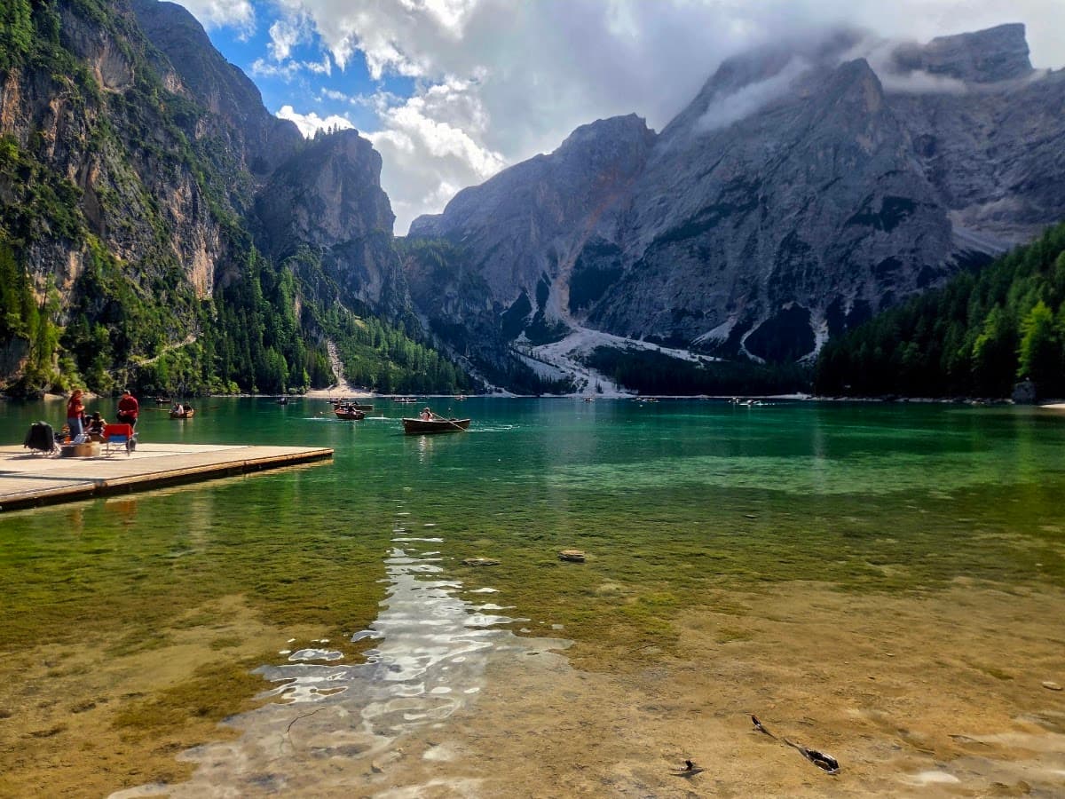 Wooden rowboats on emerald alpine lake with rocky mountain peaks and wooden dock