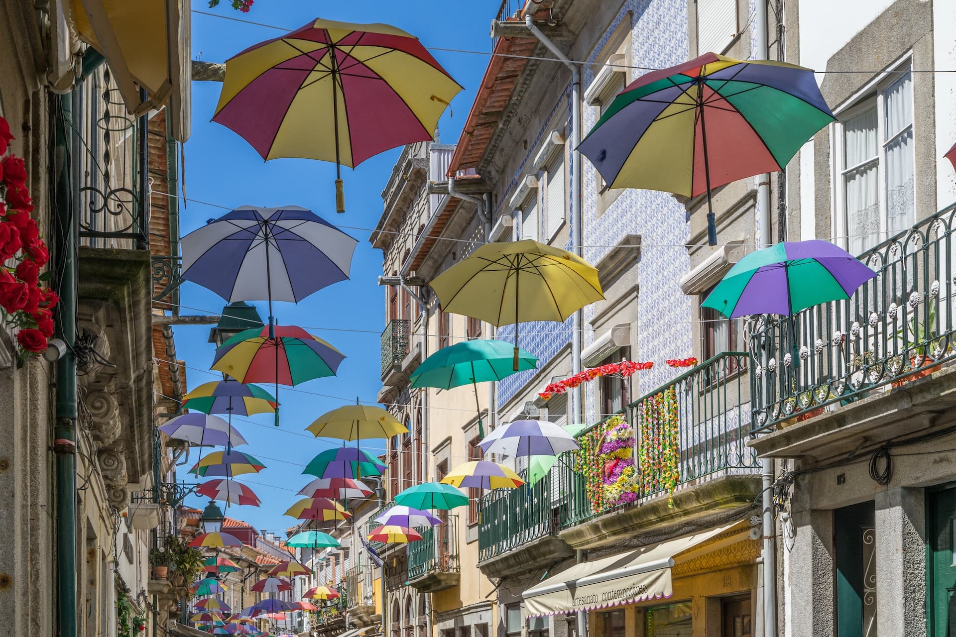 Colorful umbrellas suspended over a narrow street with traditional buildings in Viana do Castelo, Portugal.