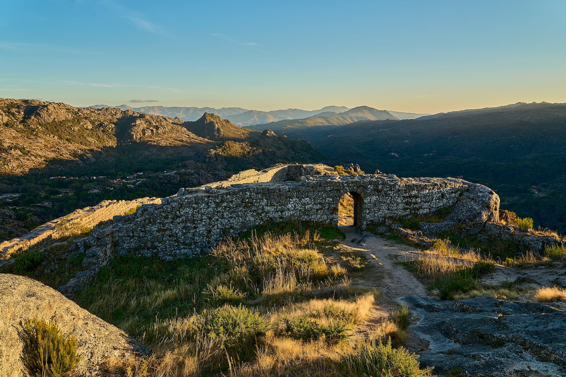 Medieval castle ruins of Castro Laboreiro high on a cliff in the mountains at sunset.
