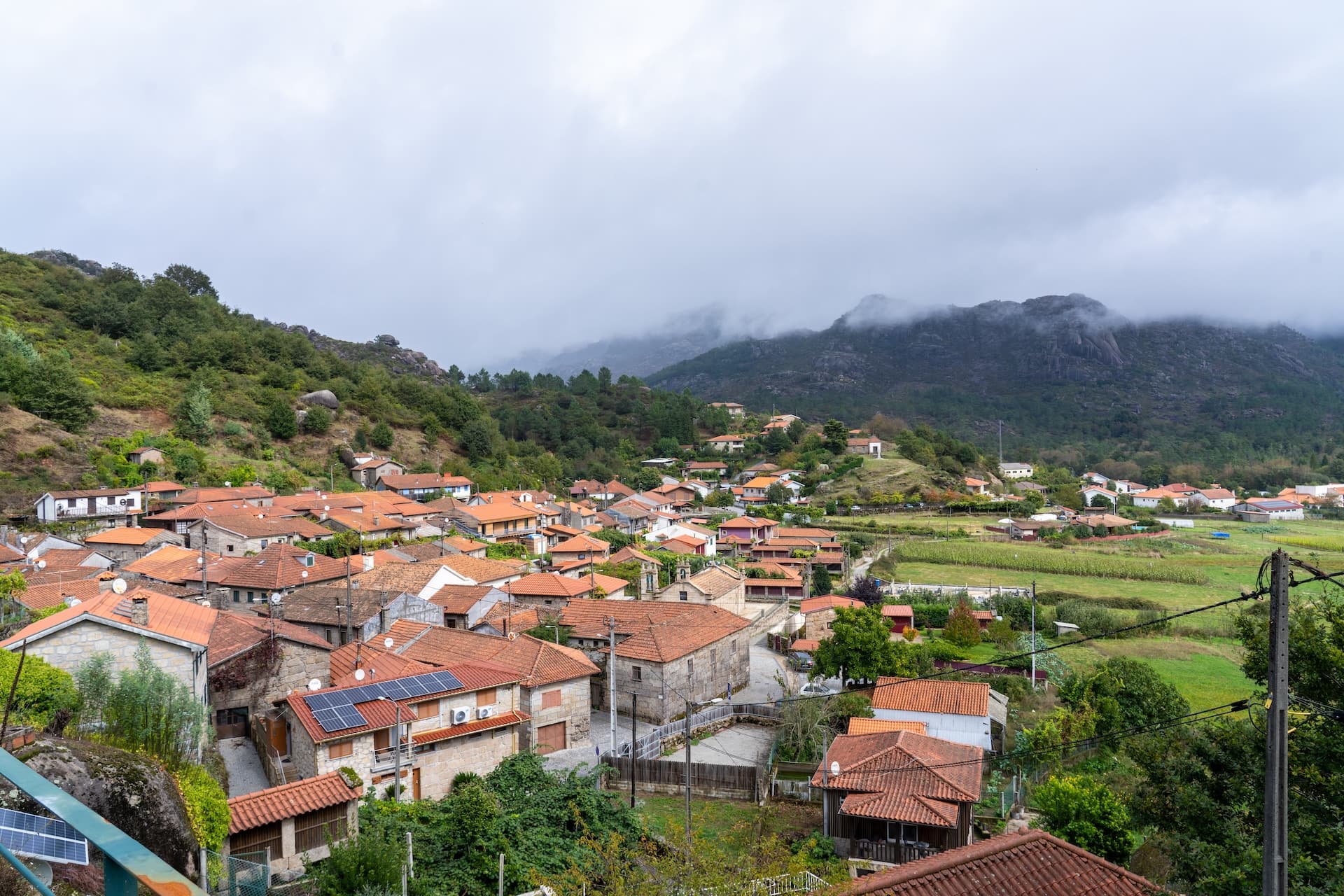 Village with terracotta roofs nestled near mountains shrouded in mist in Peneda-Geres National Park.