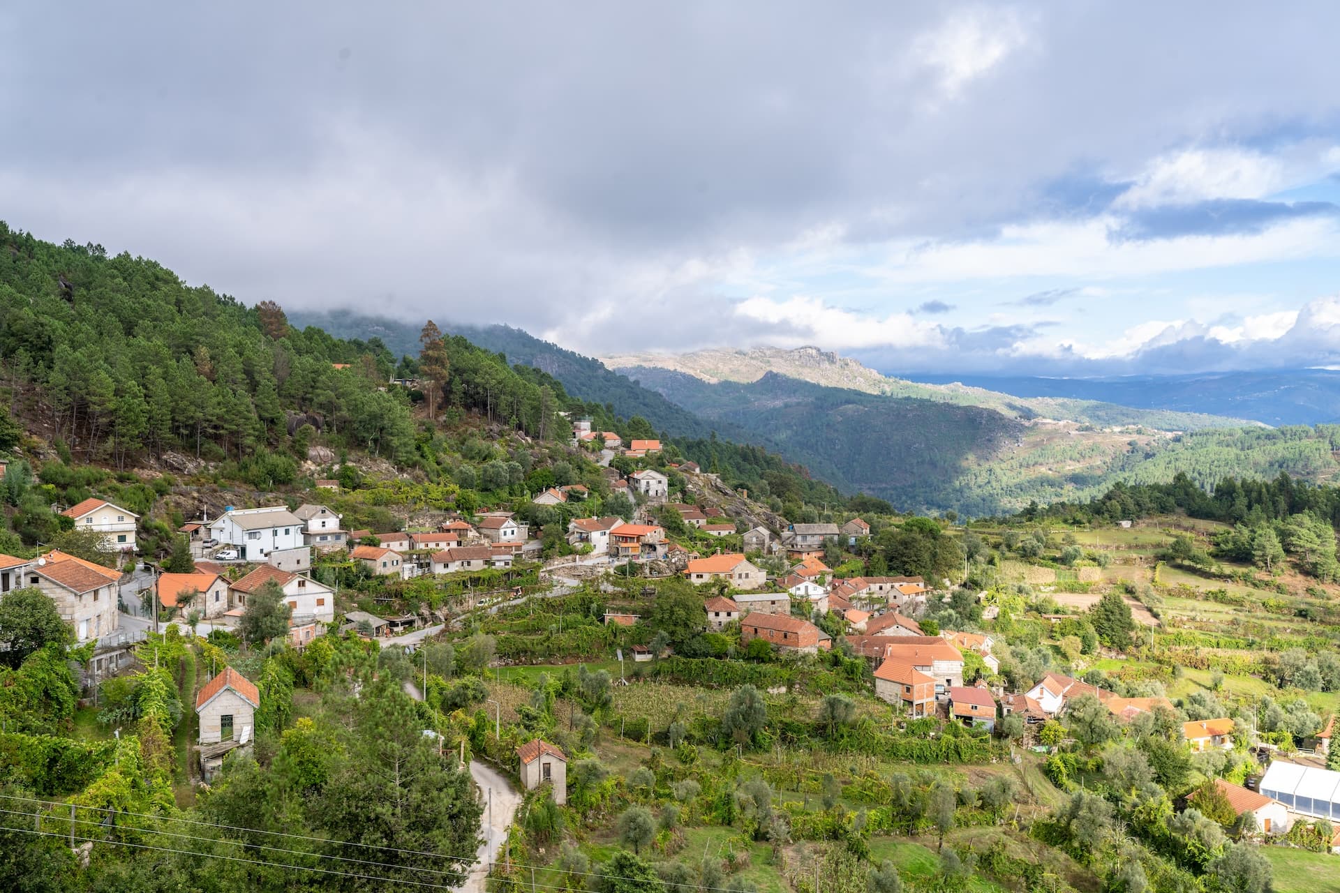 Village nestled in green mountainsides in Ermida, Portugal under cloudy skies.