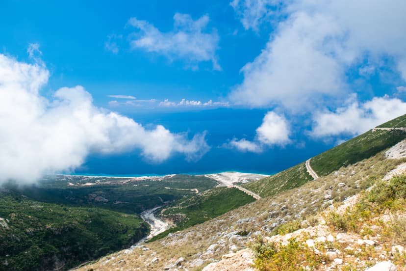 Mountain slopes overlooking blue sea and coastline under cloudy sky