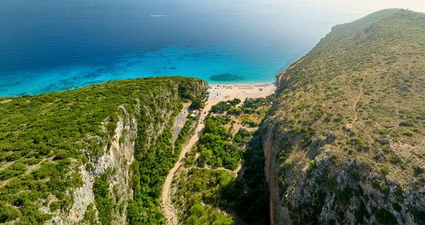 Aerial view of a coastal valley leading to a sandy beach and blue sea