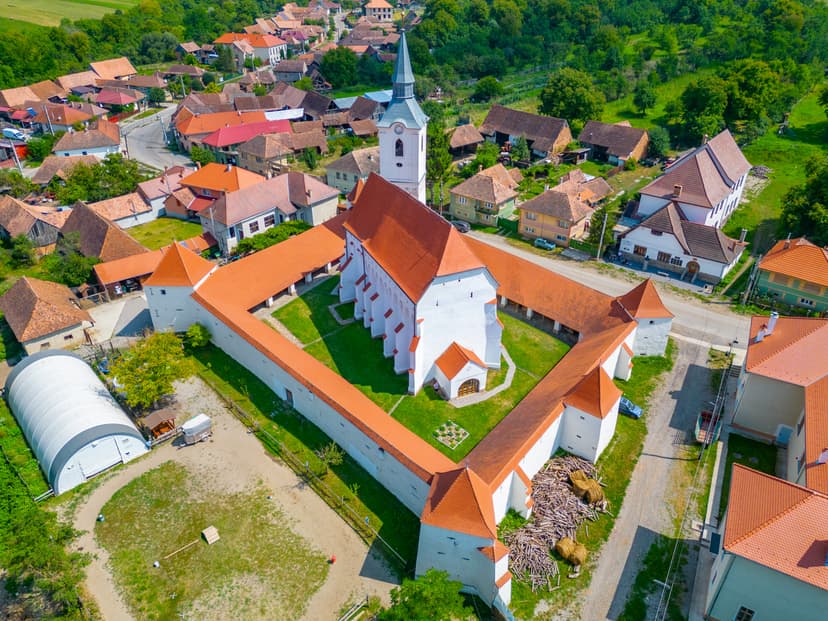 Aerial view of a fortified church with red tile roofs in a European village