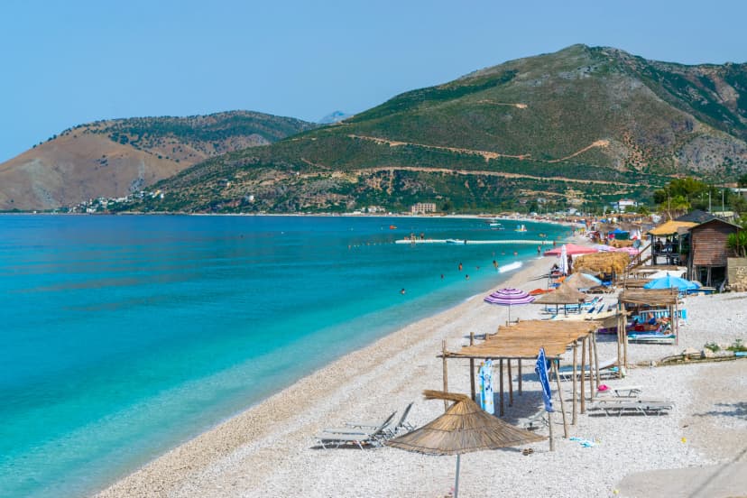 Vacationers on pebble Borsh beach with clear blue water. Albania. Ionian Sea. Ionian Sea.