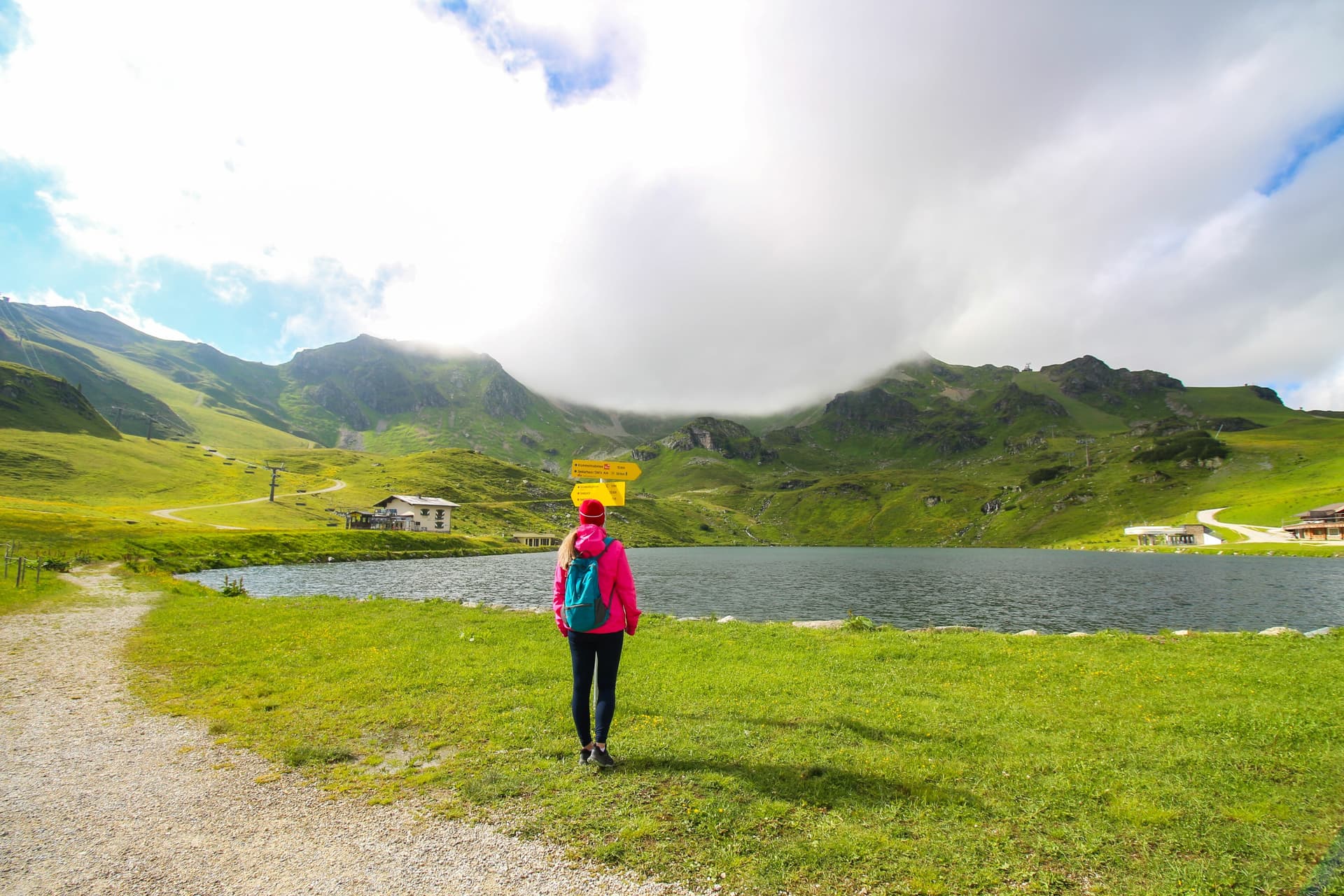 Hiker by Grunwaldsee lake with green mountains and fog in Obertauern, Austria.