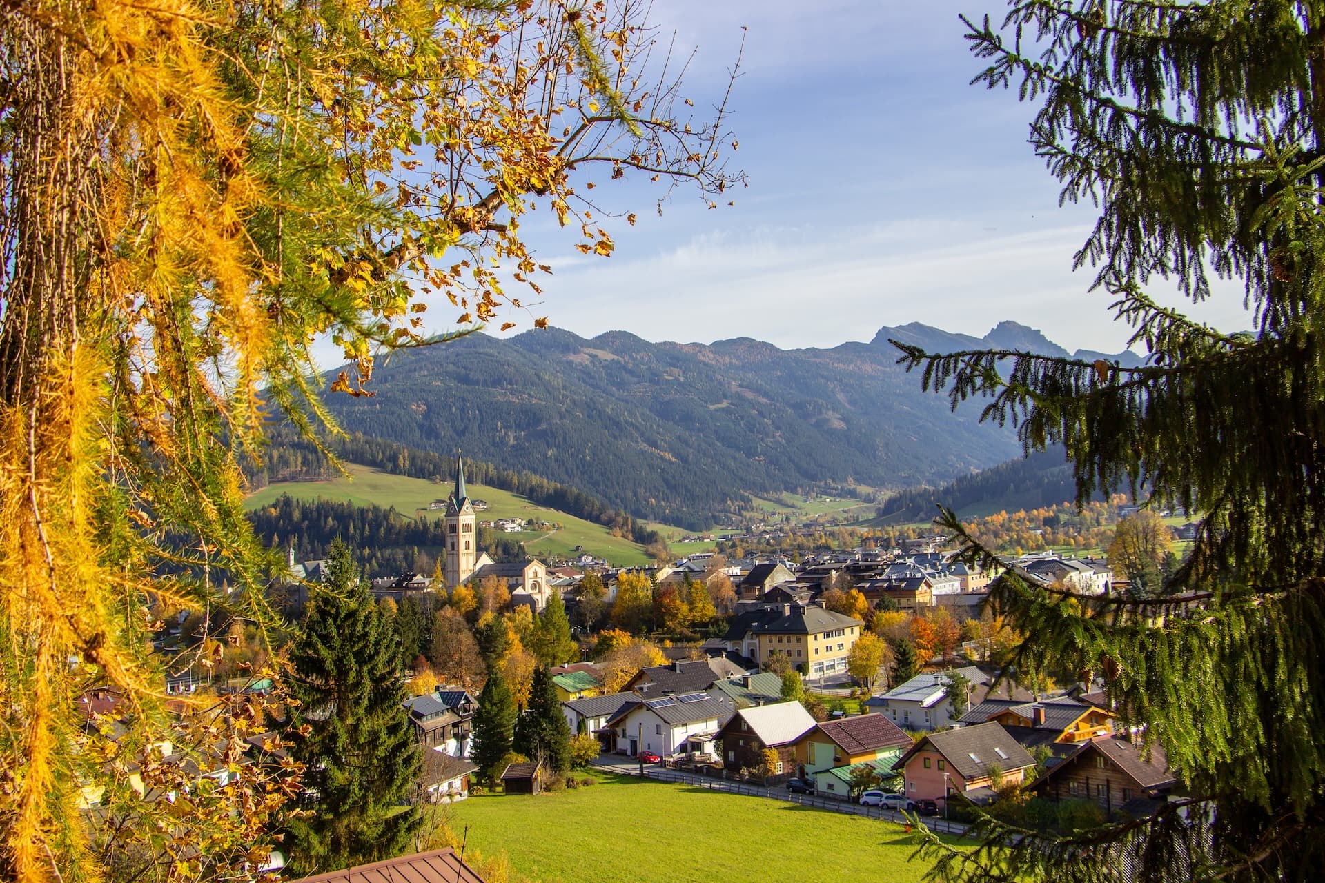 Alpine village of Radstadt with church tower, autumn foliage, and mountains in background