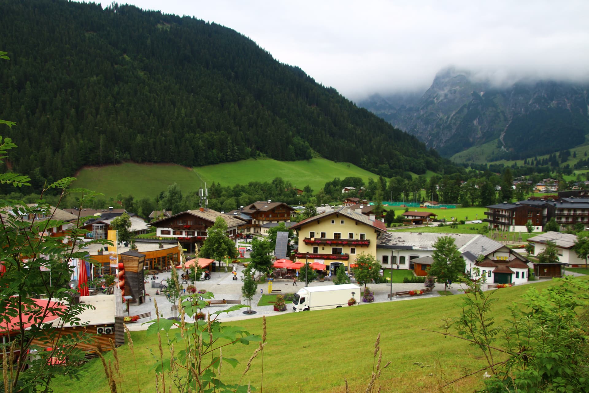 Alpine village with traditional buildings nestled below steep, forested mountains in Werfenweng.