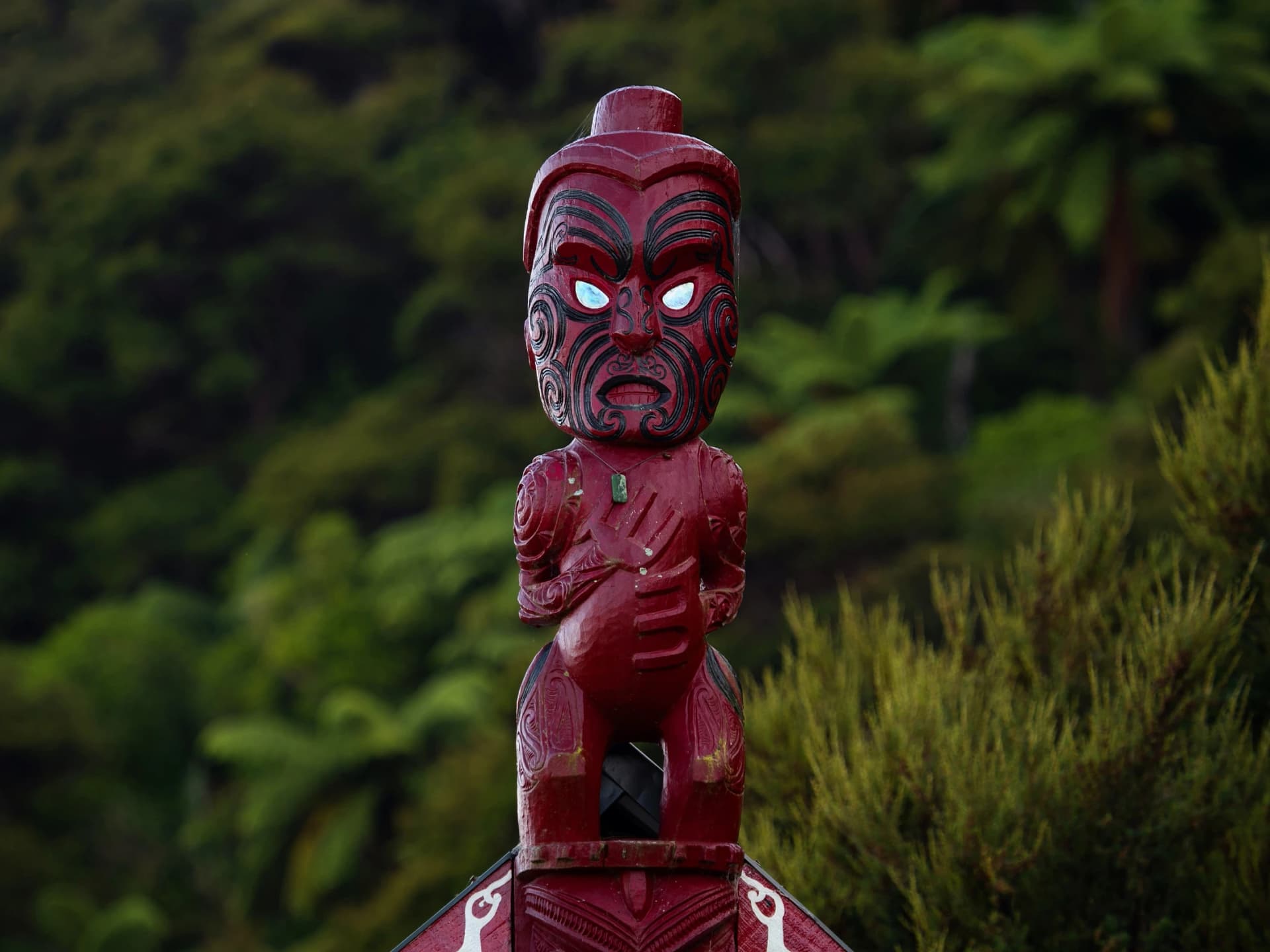 Traditional ancient red wooden Maori sculpture figure in Abel Tasman National Park Tasman South Island New Zealand