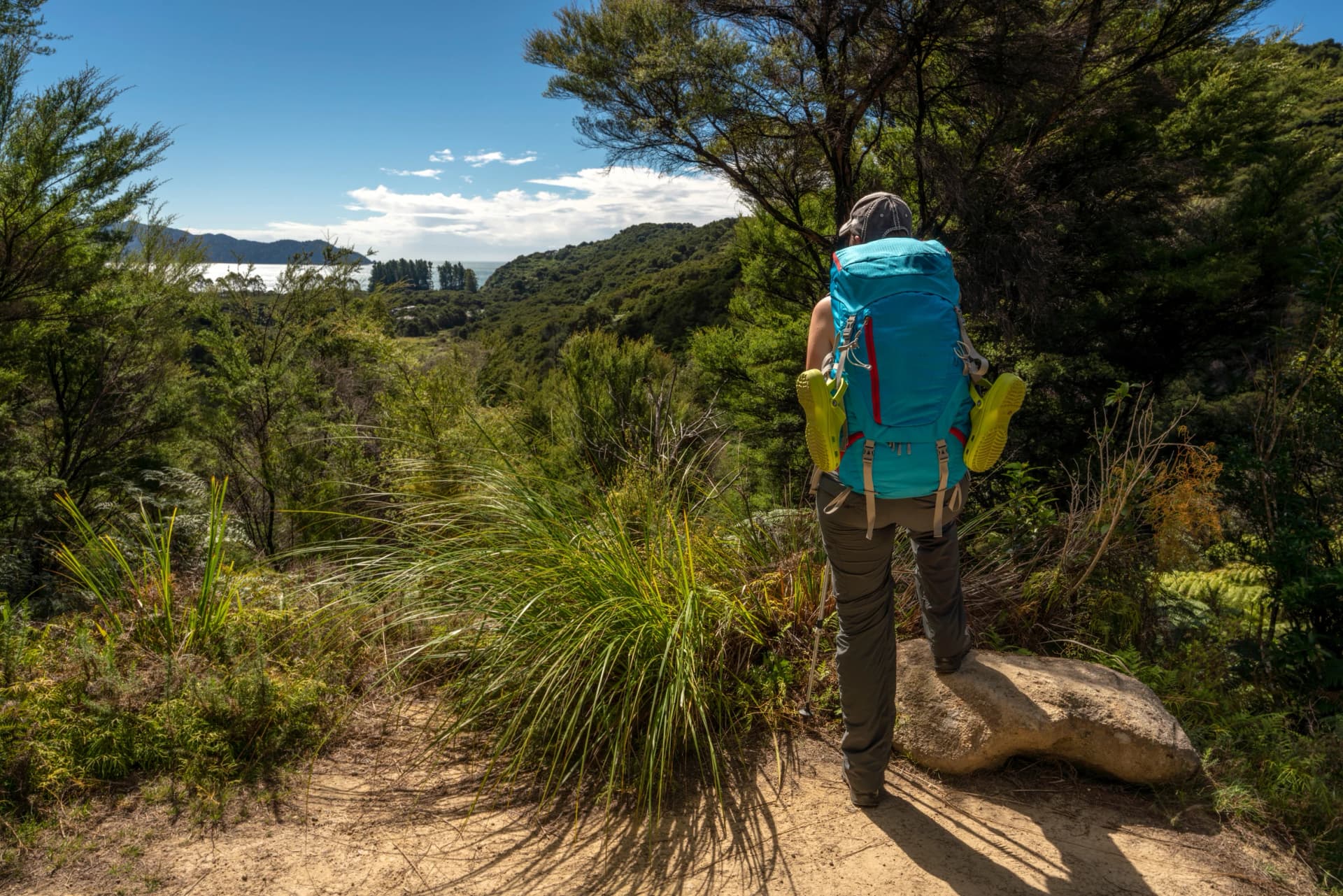 A woman and her backpack hiking the Great Walk in the Abel Tasman National Park in New Zealand.