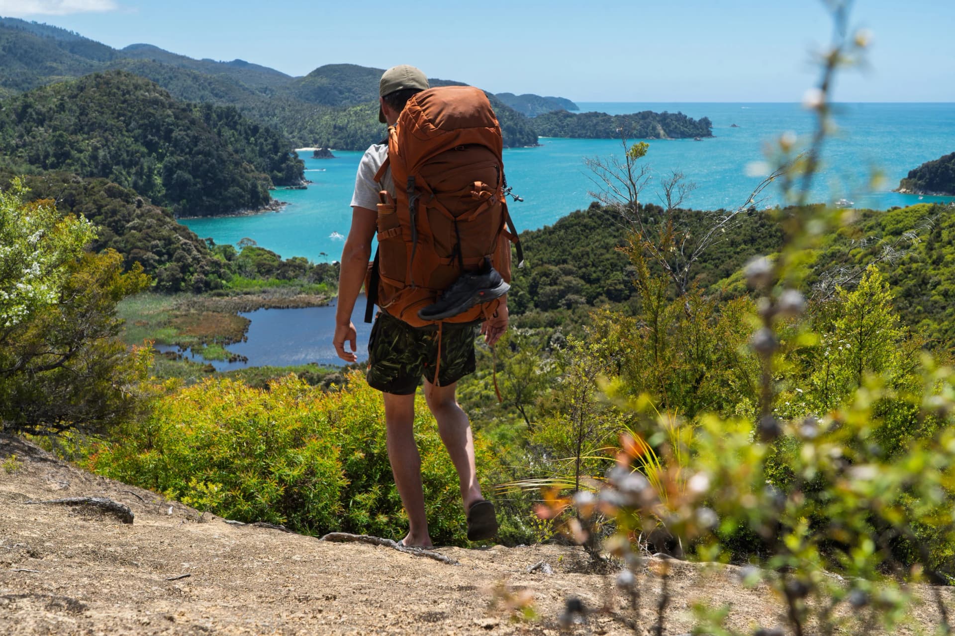 Hiker wearing flip flops backpacking Abel Tasman Coast Track, New Zealand