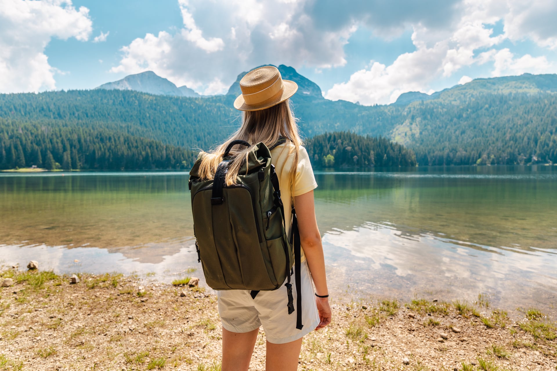 Wanderer mit Rucksack, der auf einen alpinen See und Berge schaut