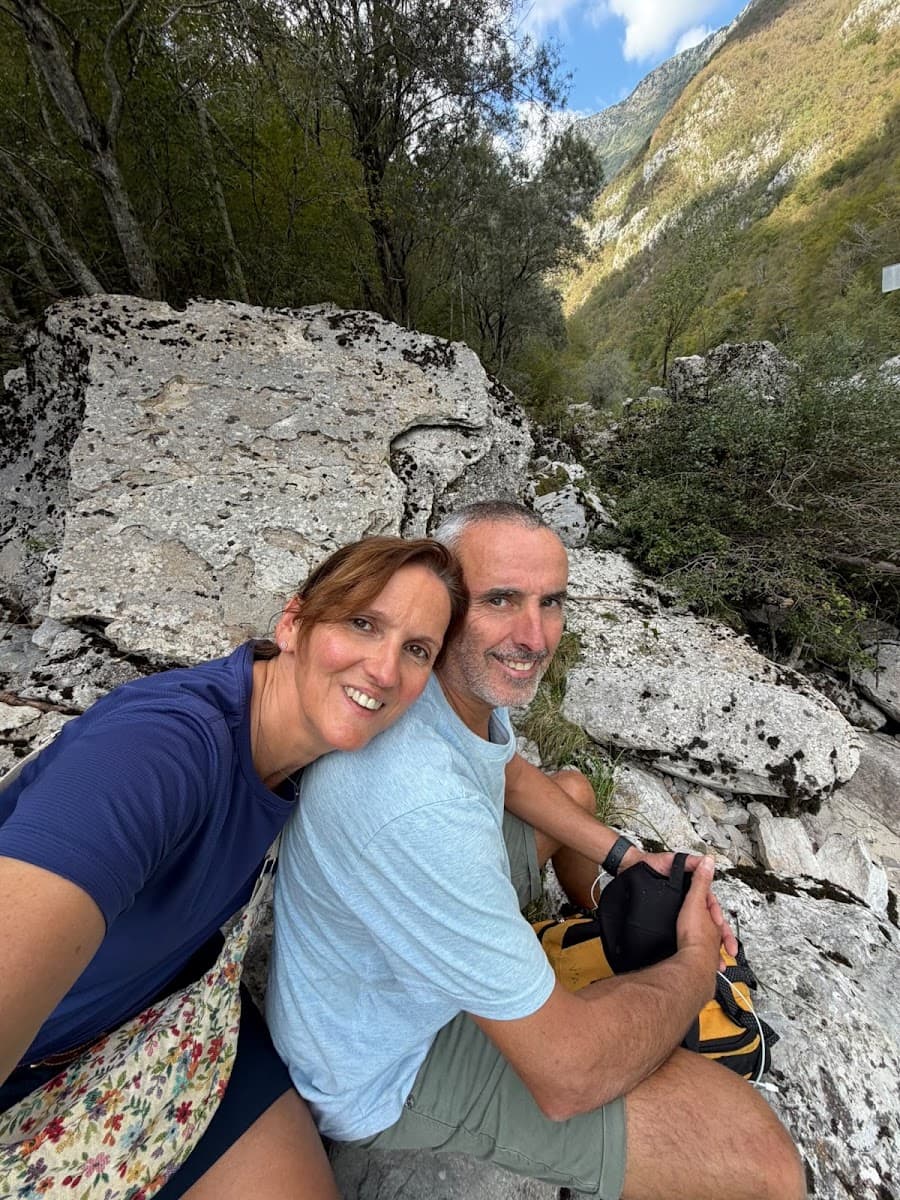 Couple hiking and posing for a selfie among rocky mountain terrain and trees