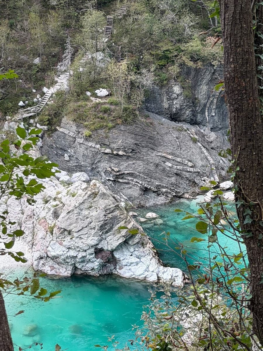 Turquoise river flowing through rocky gorge with folded rock strata and wooden stairs