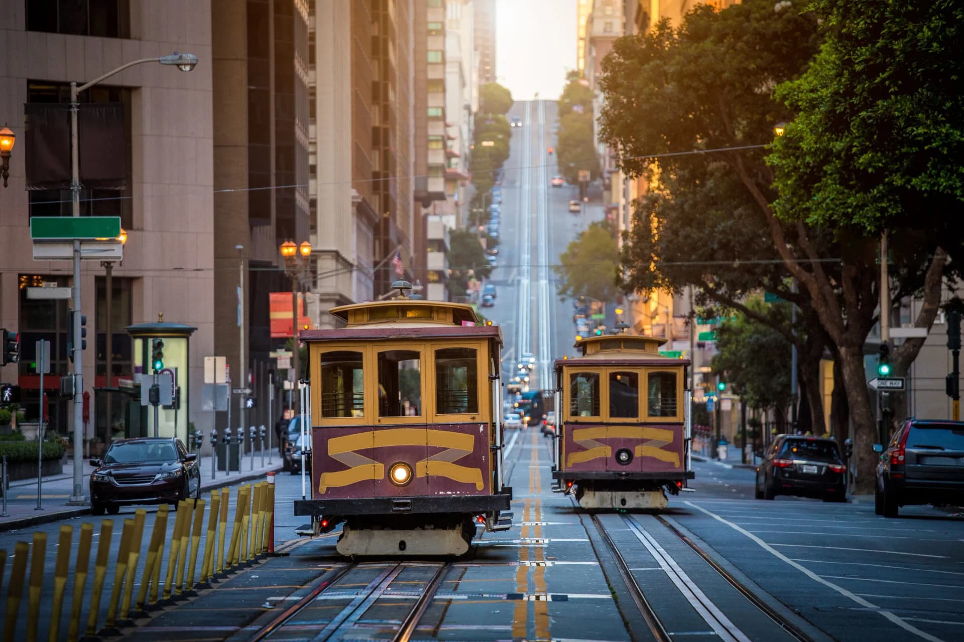 San Francisco cable cars on California Street at sunrise ascending a steep city street.