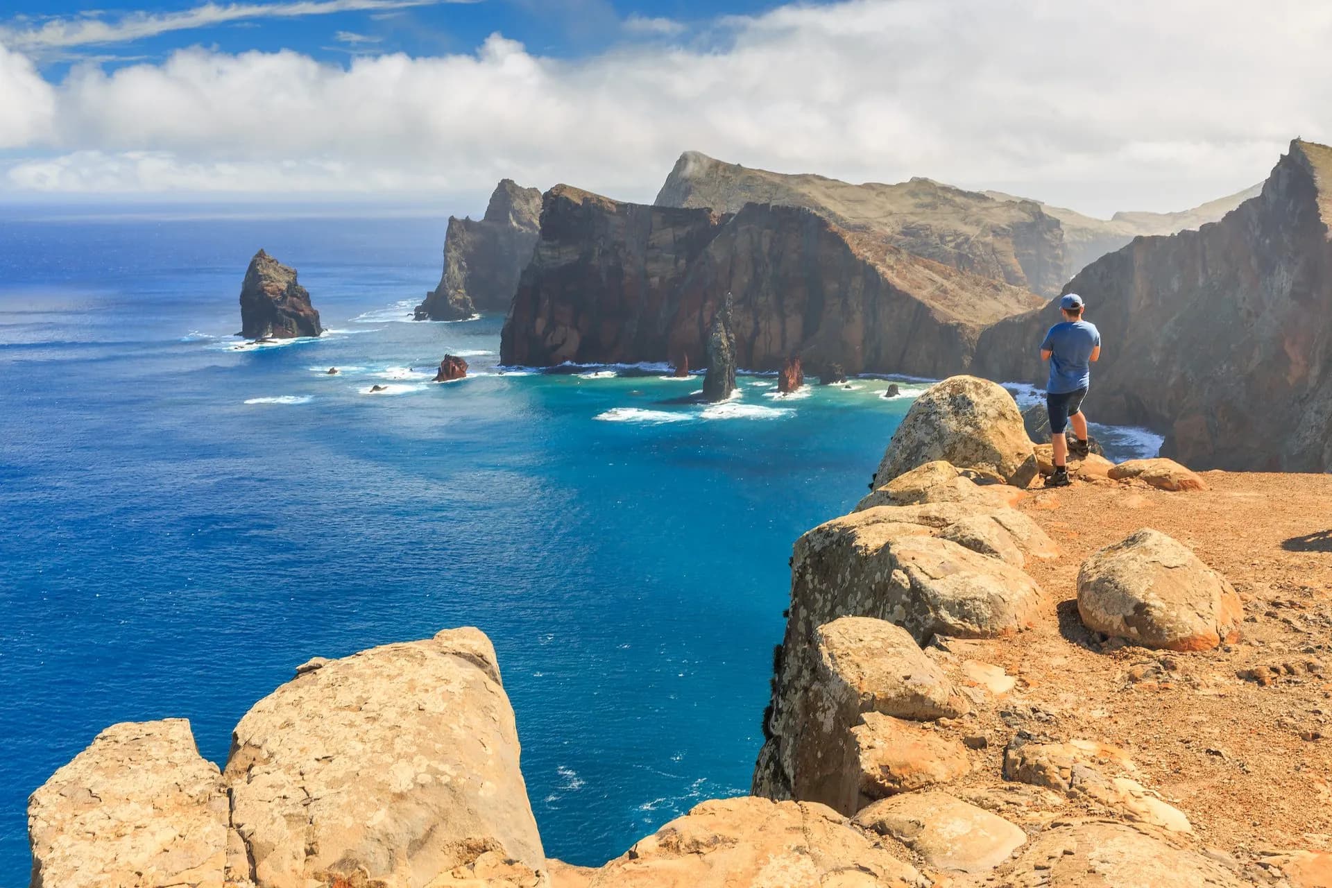 Hiker overlooking steep cliffs and sea stacks during hiking on Ponta do São Lourenço.