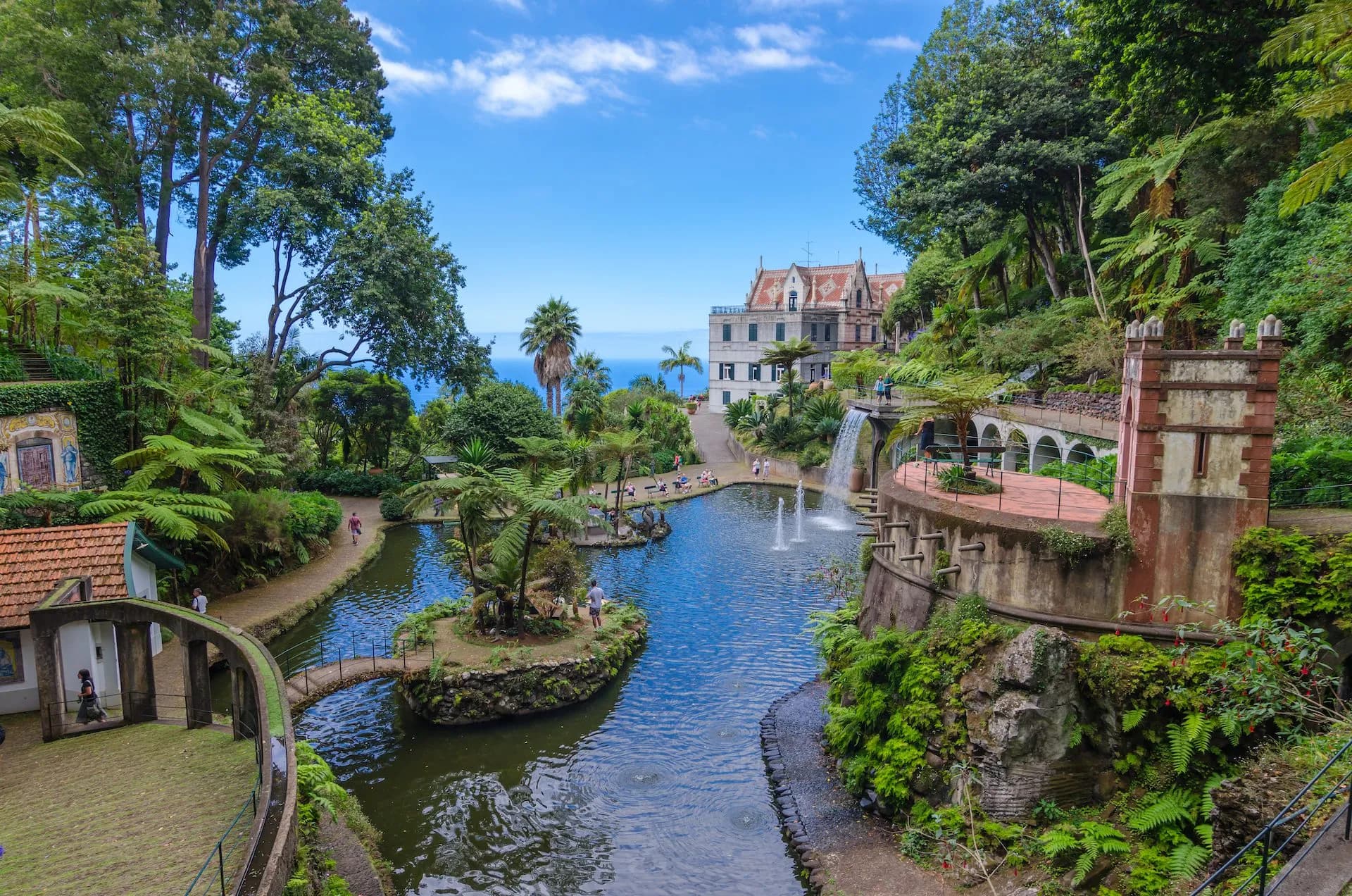 Lush tropical gardens with ponds, fountains, and historic buildings overlooking the sea in Funchal.
