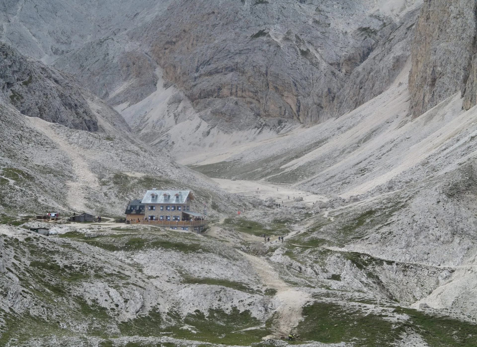 Rifugio Antermoia mountain hut nestled in a rocky valley with hikers on trails.