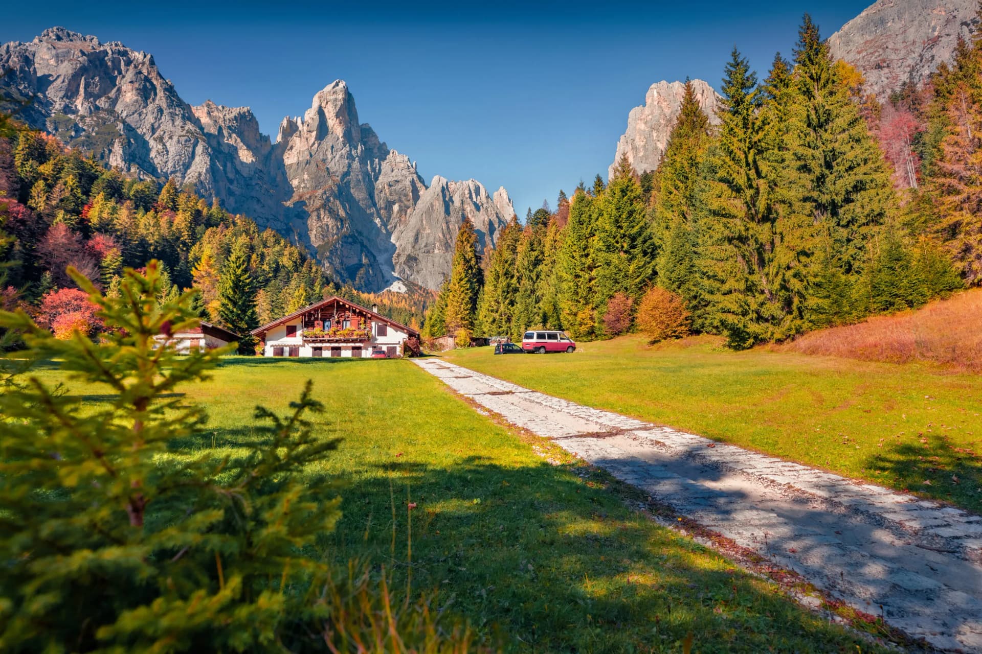 Small hotel in Pradidali Valley with autumn trees and rugged mountain backdrop