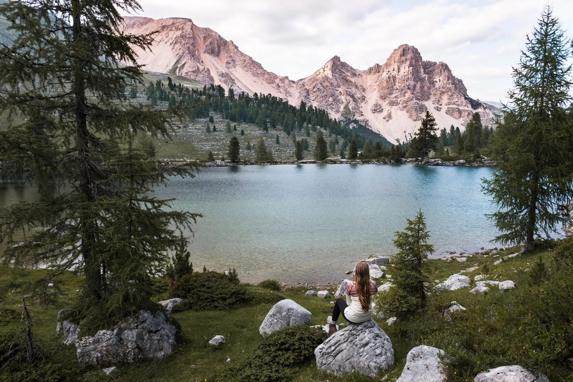 Woman sitting on rock overlooking Le Vert Lake and rugged mountains.