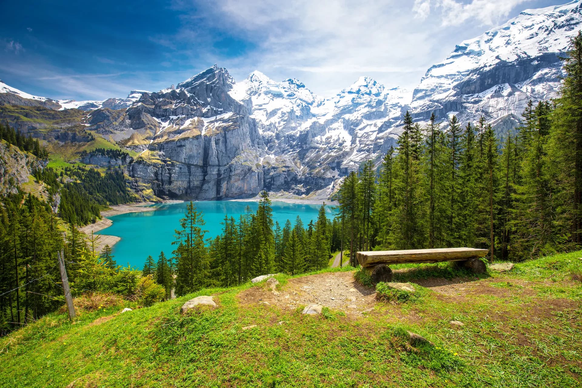 Turquoise Oeschinnensee lake with waterfalls and snow-capped Swiss Alps above Kandersteg.